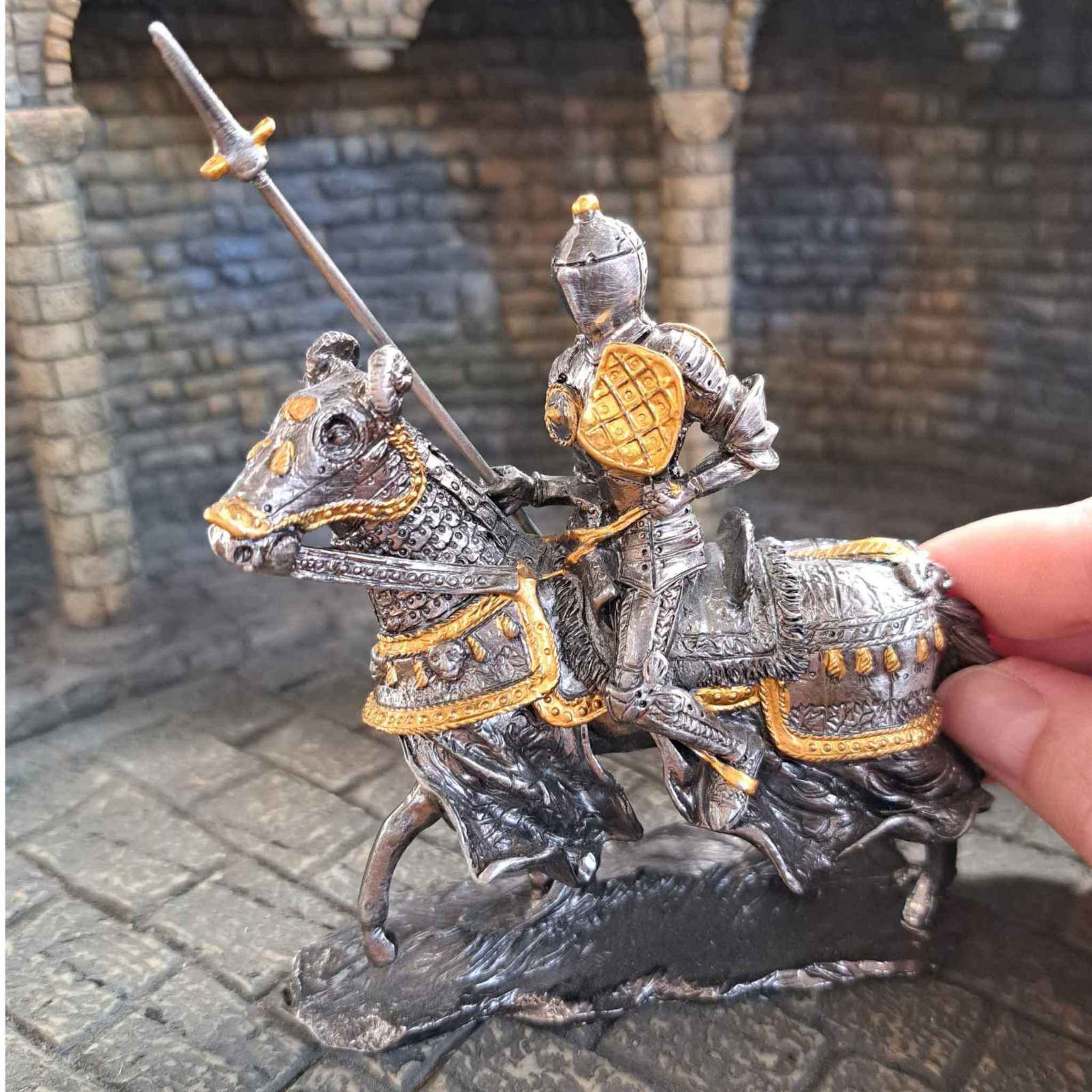 Metal Statue of a jousting tournament knight with hand pictured for scale