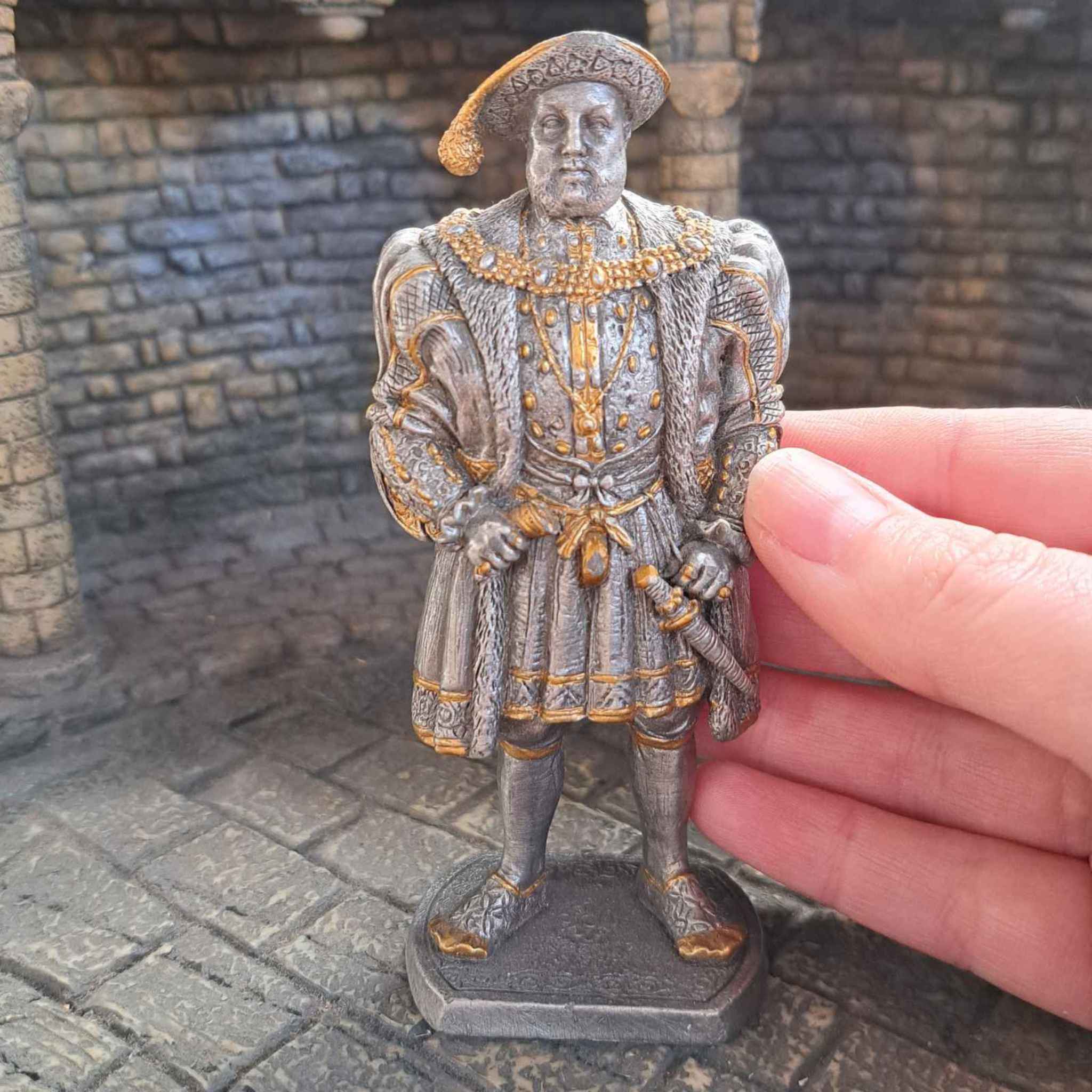 Henry VIII metal model with hand pictured for scale